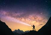 a man shines a flashlight in the starry night